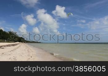 a kite surfer hangs onto his kite in the water at a beautiful beach
