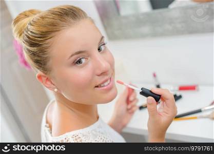 a lady is applying lip gloss