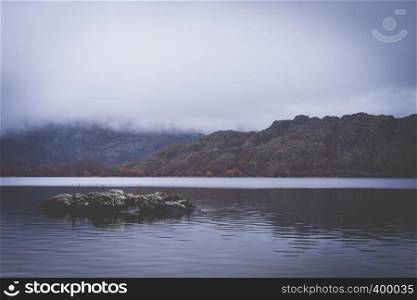 A lake between mountains with low clouds