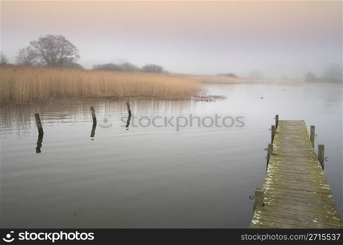 a lake in denmark in the winter time with a foggy weather