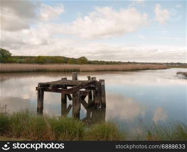 a landscape shot of a beautiful serene lake with a wooden structure rotting platform
