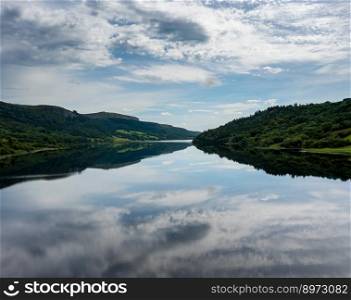 A landscape view of Glencar Lough in western Ireland with sky reflections in the calm lake water