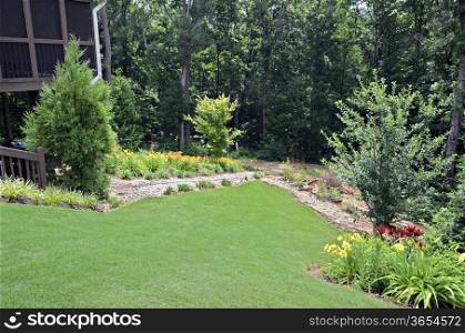 A landscaped yard with flowers and garden on a slopping lot.