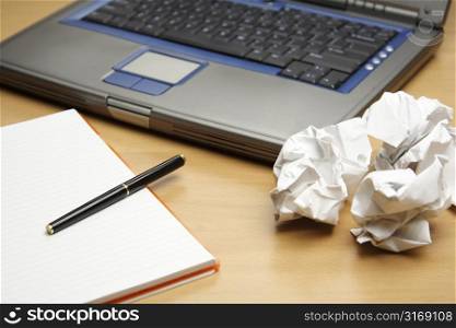 A laptop and a notebook with crumpled paper, can be used as business planning concept