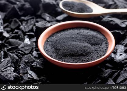 A large amount of fine charcoal is placed in a cup on top of a pile of charcoal.