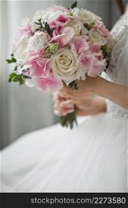 A large bouquet of white and pink roses in the hands of the bride.. The silhouette of the bride holding a bouquet of delicate roses in her han