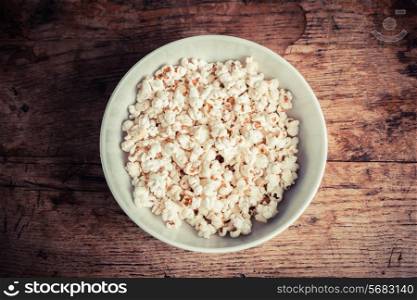 A large bowl of popcorn on a wooden table
