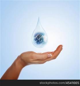 A large drop of water with mountain inside and hands to support it. The symbol of environmental protection.