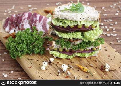 A large energy-boosting sandwich with vegetables, ham and bread with seeds