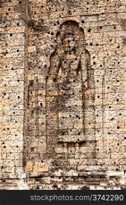 A large female figure is built into the bricks of a wall niche in the East Mebon temple near Angkor Wat. The holes in the brick were used to hold plaster that covered the temple walls in ancient times.