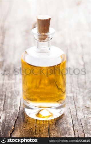 A large glass bottle of essential oil on a wooden floor. The essential oil