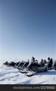 A large group of snowmobiles on a barren winter landscape