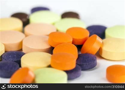 A large number of multi-colored tablets of different shapes and purposes with different medical properties lying together in a heap. multi-colored tablets