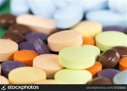 A large number of multi-colored tablets of different shapes and purposes with different medical properties lying together in a heap. multi-colored tablets