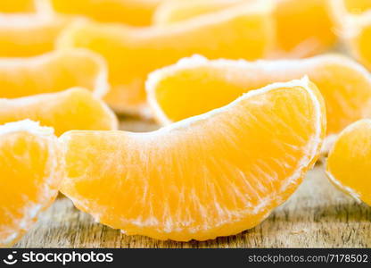 a large number of slices of purified mandarin on a wooden board, close-up of citrus in winter. mandarin on a wooden board