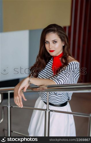 A large portrait of a beautiful girl in a striped blouse and a red scarf around her neck.. A wonderful girl with long thick hair close-up 4177.