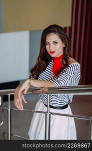 A large portrait of a beautiful girl in a striped blouse and a red scarf around her neck.. A wonderful girl with long thick hair close-up 4177.