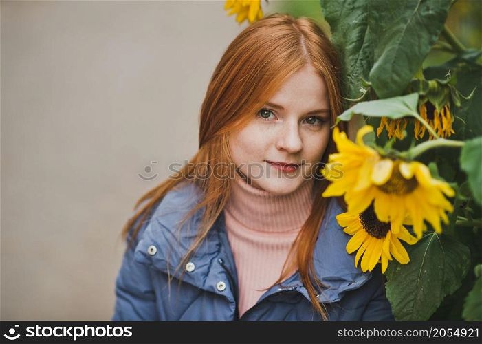 A large portrait of a red-haired girl against the background of nature.. A girl on the background of sunflowers in autumn 2752.
