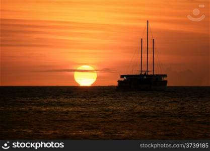 A large sailing boat silhouetted against a golden sunset at Gili Lankanfushi in the Maldives