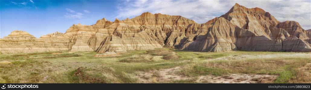 A large-scale panoramic view of a part of Badlands National Park in South Dakota showcases the grasslands and the hills of the area.
