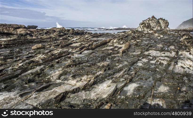 A layer of rocks extend out to the ocean at the Storms River Mouth in the Western Cape, South Africa.