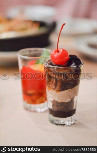 a layered chocolate , garnished with cherries in glass