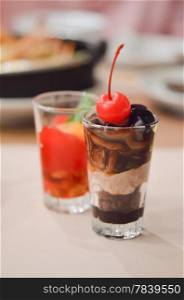 a layered chocolate , garnished with cherries in glass