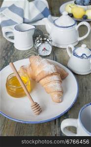 A light breakfast consisting of a cup of tea and croissants with a honey