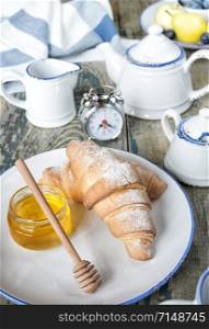 A light breakfast consisting of a cup of tea and croissants with a honey