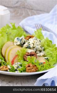 A light lettuce salad with pear slices, gorgonzola pieces and walnut seasoned with olive oil