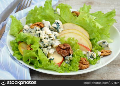 A light lettuce salad with pear slices, gorgonzola pieces and walnut seasoned with olive oil