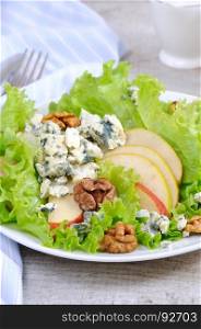 A light lettuce salad with pear slices, gorgonzola pieces and walnut seasoned with olive oil