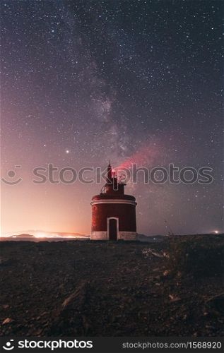 A lighthouse during the night with the milky way behind