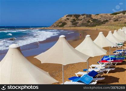 A line of umbrellas and sunbeds in Davlos beach, island of Cyprus