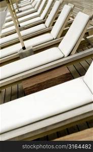 A line of wooden sunbeds with white plastic covers