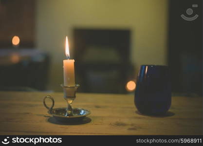 A lit candle and a blue glass on a table in a dining room