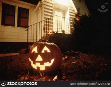 a lit pumpkin outside a house