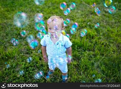 A little 16 month-old boy is looking at soap-bubbles. Baby&rsquo;s dreams.