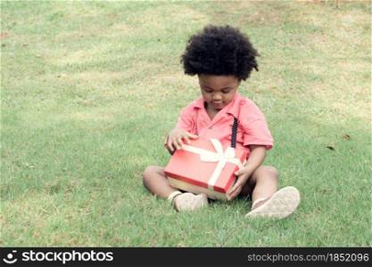 A little African boy is playing in backyard while openning gift box on his birthday