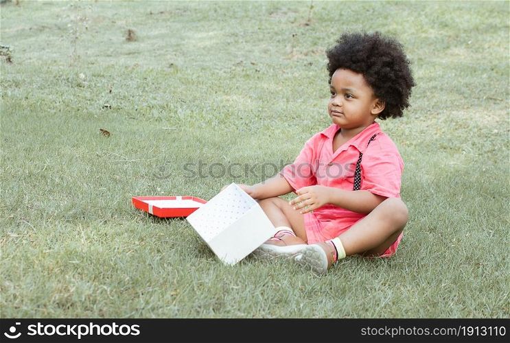 A little African boy is playing in backyard while openning gift box on his birthday