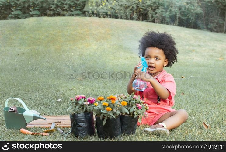 A little African boy is playing with blur foreground of colorful flowers. Education, Environment and Lifestyle Concept.