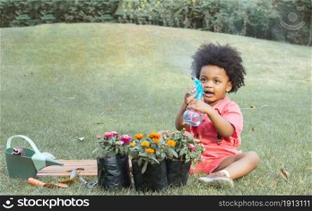 A little African boy is playing with blur foreground of colorful flowers. Education, Environment and Lifestyle Concept.