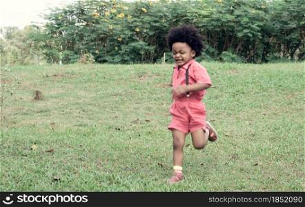 A little African boy wearing pink shirt is playing in backyard