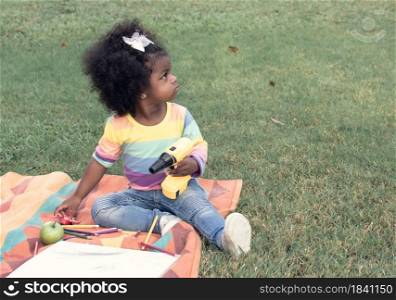A little African girl wearing colorful shirt is playing in backyard