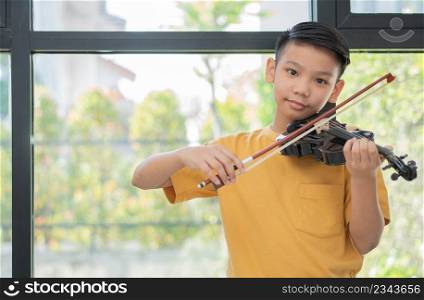 A Little Asian kid playing and practice violin musical string instrument against in home, Concept of Musical education, Inspiration, Teenager art school student.