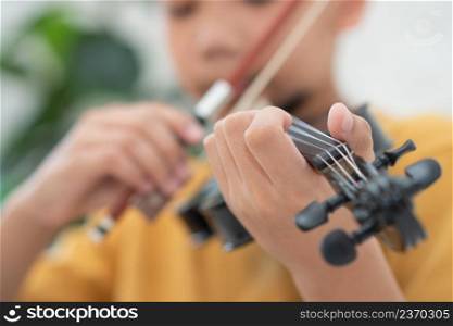 A Little Asian kid playing and practice violin musical string instrument against in home, Concept of Musical education, Inspiration, Teenager art school student, Selective focus.