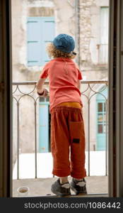 a little blond boy looking out the window, back view
