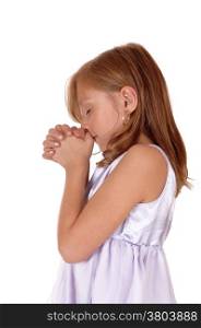 A little blond girl standing in profile with her hands folded and praying,isolated for white background.