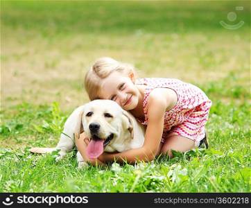 A little blond girl with her pet dog outdooors in park