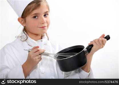 a little blonde girl dressed in chief cook is cooking